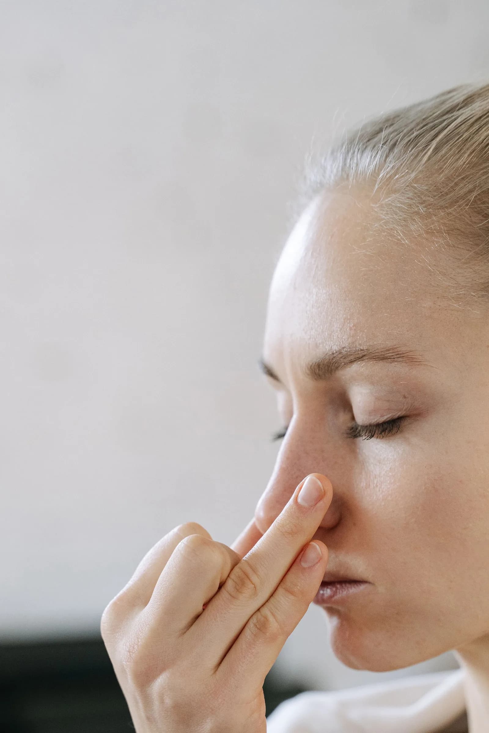 Mulher de olhos fechados pressionando a região do seio nasal com os dedos